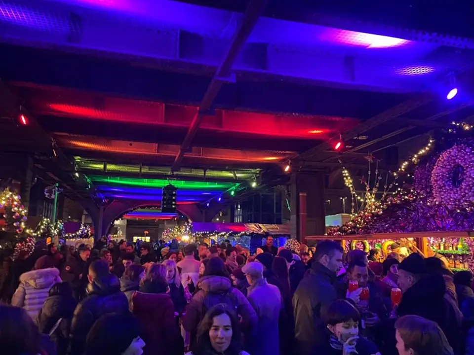 Besucher flanieren über den belebten Weihnachtsmarkt, die Christmas Avenue, unter bunten Lichtern, die eine festliche Atmosphäre schaffen und die Vorfreude auf die Feierlichkeiten