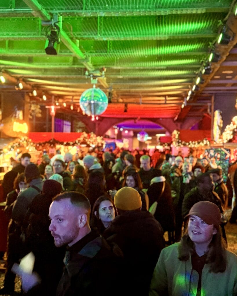 Viele Menschen besuchen eine Veranstaltung mit Discokugel, die von der Decke hängt und für stimmungsvolles Licht sorgt.
