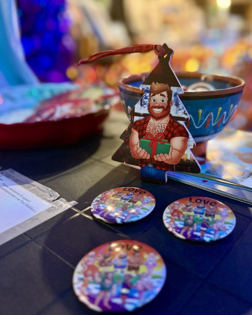 Eine Weihnachtsbaumfigur mit Bären-Motiv und 'Love'-Buttons liegen auf einem Tisch bei einer Veranstaltung.